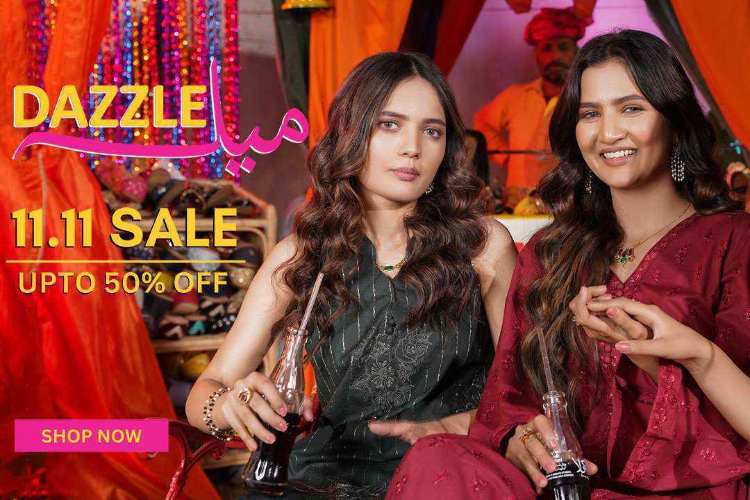 Two women in traditional Pakistani attire smiling and holding drinks, 11.11 sale banner, festive decor.