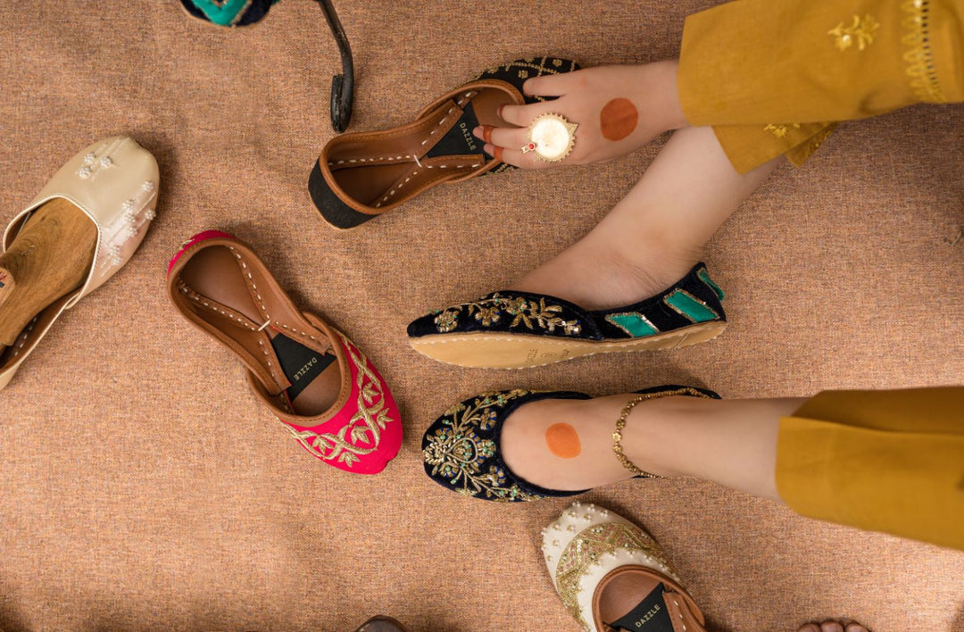 Women's traditional embroidered khussa shoes in vibrant colors, flat lay on brown fabric.